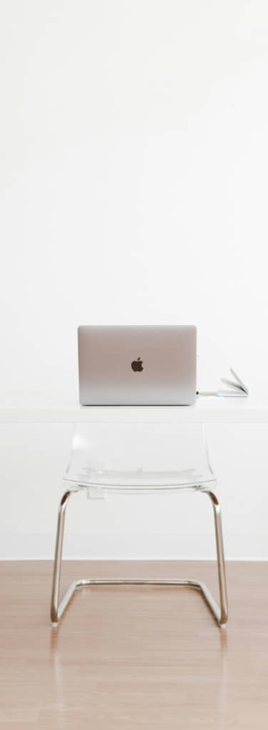 A ghost desk and chair with a laptop open sitting on top