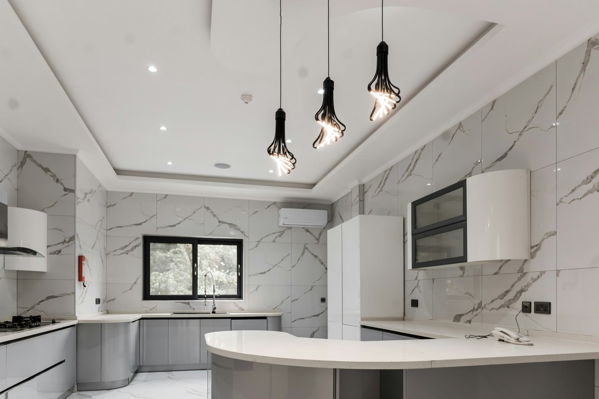 modern kitchen with stone tile walls and three pendant lights
